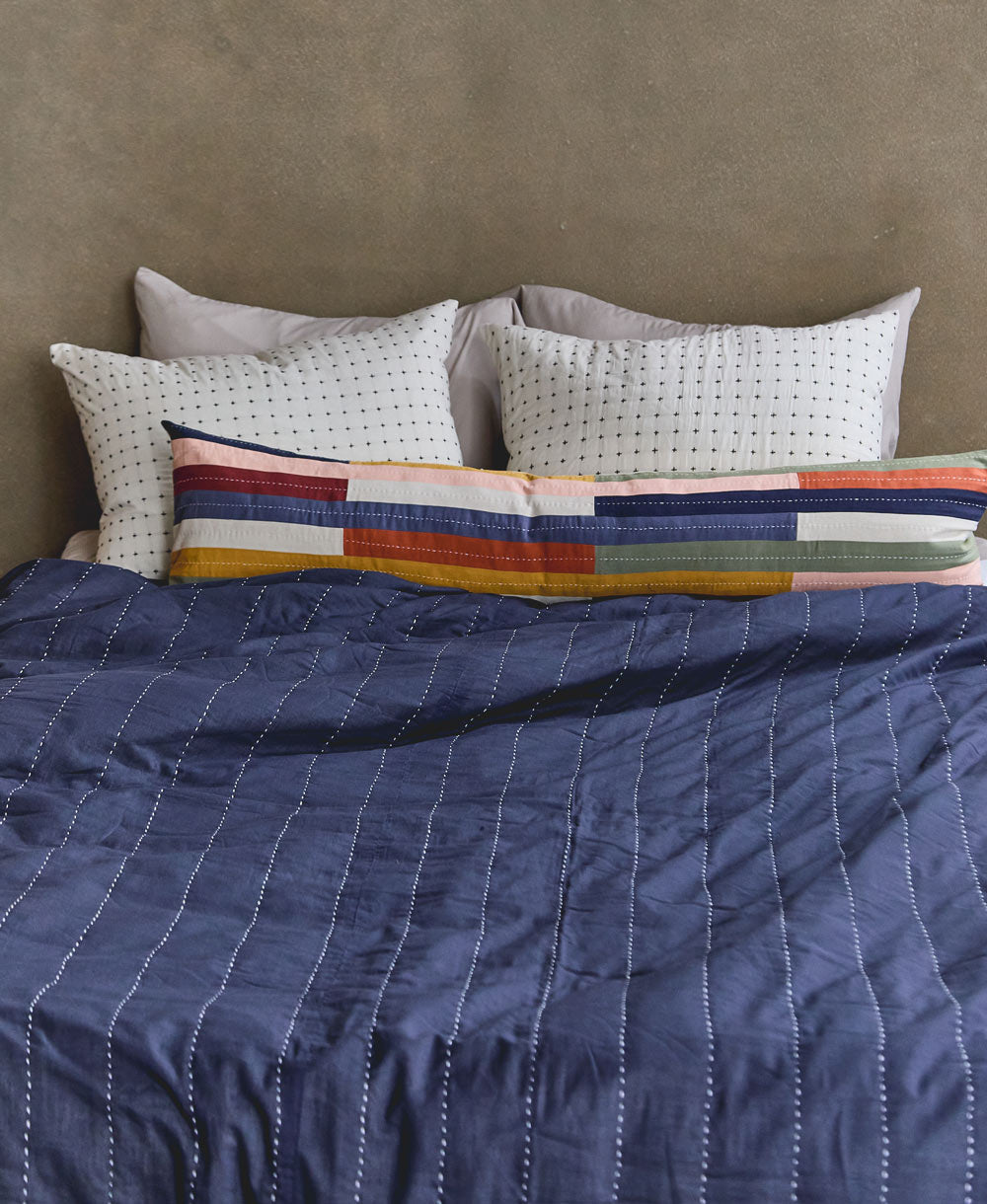 Colcha patchwork Multi-Check con cojínes sobre una cama