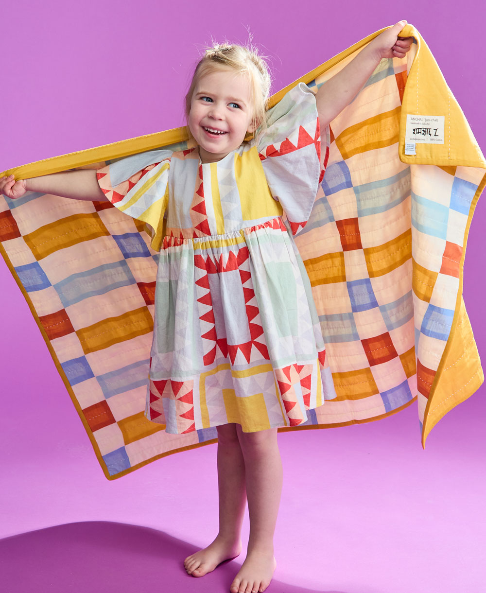 Niña sosteniendo el Tile Baby Quilt